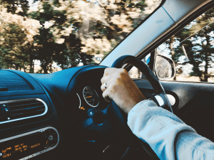 Pessoa com a mão no volante de um carro, prestes a dar a partida, em ambiente iluminado.