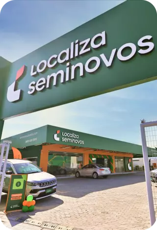 Fachada da loja Localiza Seminovos, destacando o logotipo da empresa em um painel verde e uma área de estacionamento com carros disponíveis para venda